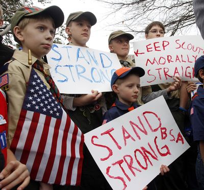 Clockwise from left, Boy Scouts Eric Kusterer, Jacob Sorah, James Sorah, Micah Brownlee and Cub Scout John Sorah hold signs at the Boy Scouts national headquarters in Irving, Texas, on Wednesday. (Associated Press)