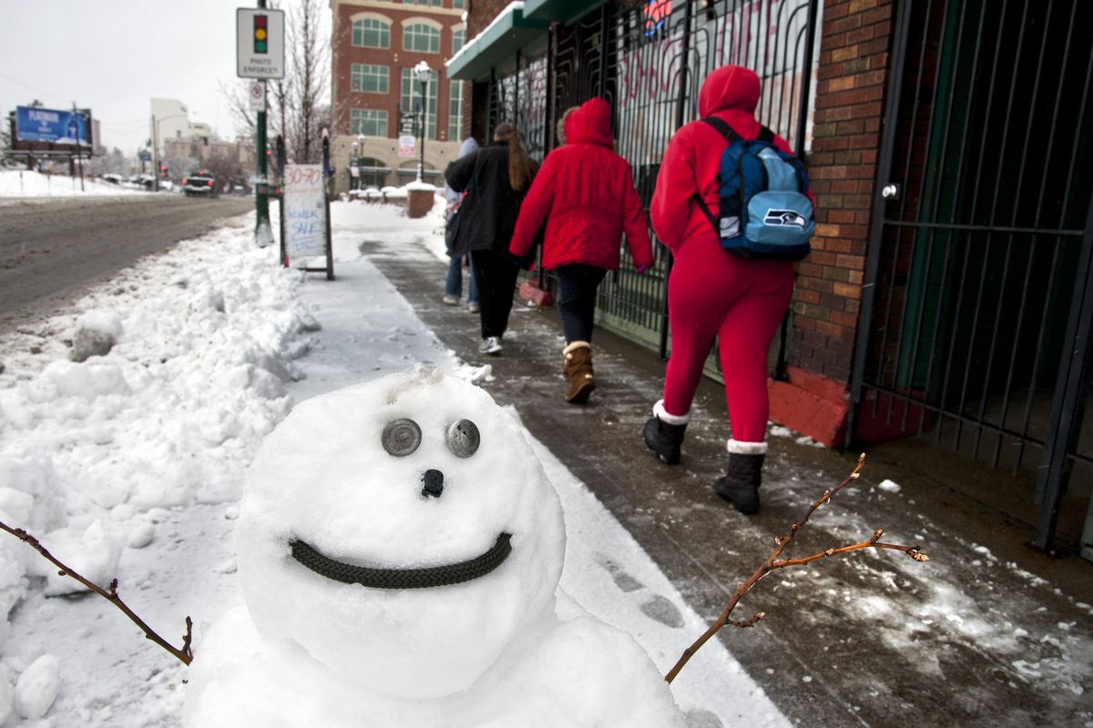 Pedestrians walk west on Sprague Avenue at Division Street past an urban snowman outside the Mountain Goat Outfitters store on Monday in Spokane. The store’s manager, Shane Collins, said it was easier to build the snowman than it was to shovel the snow off the sidewalk. His goal was to “keep the holiday cheer going.” The snowman’s eyes are climbing bolts and the mouth is a length of climbing rope from the store. (Dan Pelle)