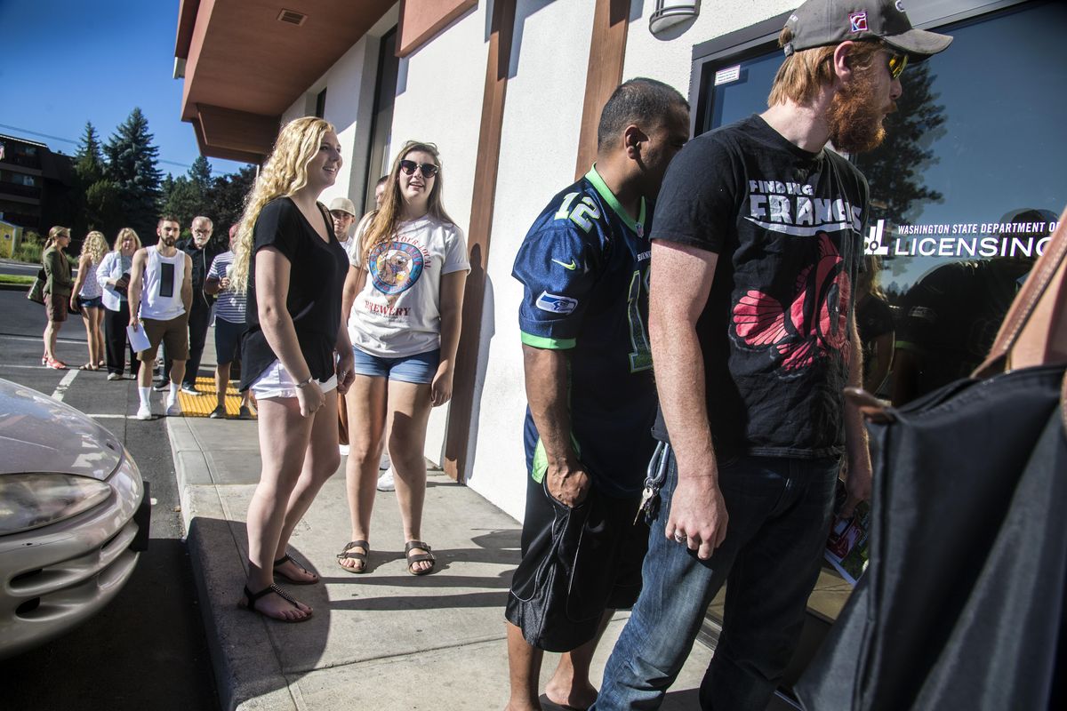 A line of people stretches out the door and into the parking lot outside the Washington State Department of Licensing on Country Homes Boulevard, Friday morning, July 28, 2017, in Spokane Wash. The building has maximum occupancy of 49. (Dan Pelle / The Spokesman-Review)