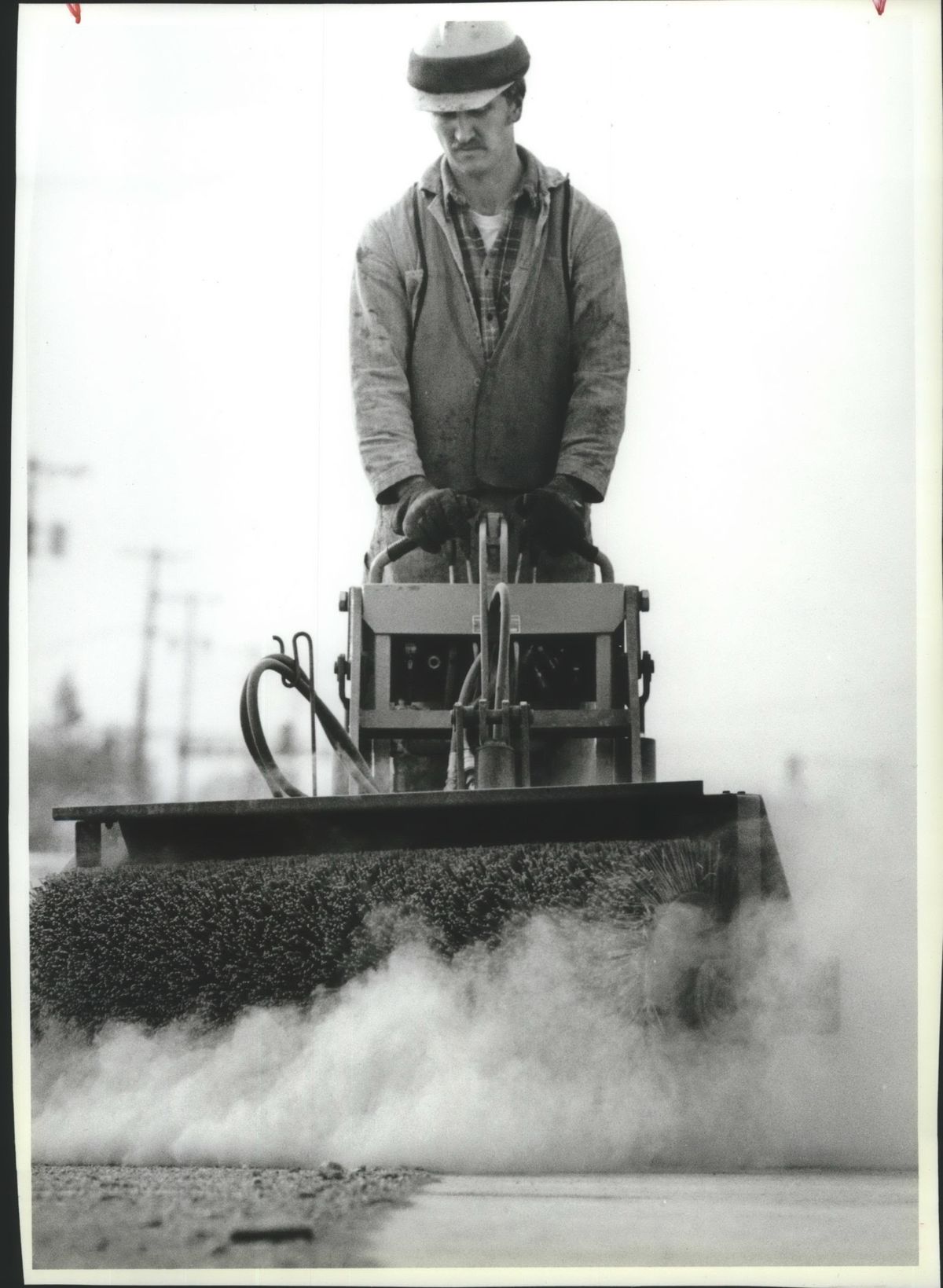 Rod Maki, of the Spokane County Road Department, operates a power brush to clear some of the accumulation from a traffic island on Sprague Avenue near University City in 1988. (Steve  Thompson / The Spokesman-Review)