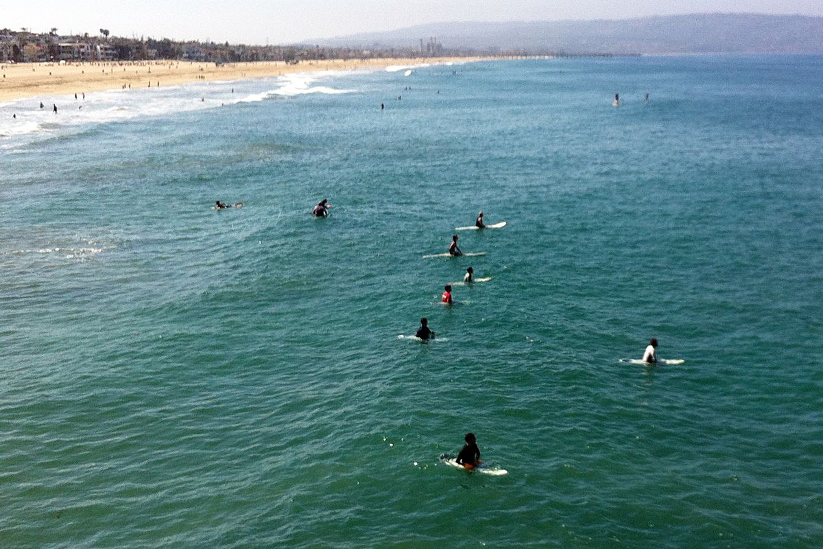Surfers and swimmers return to the ocean Sunday off Manhattan Beach. (Associated Press)