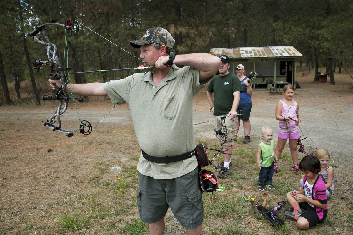 Michael Hamilton takes aim as children of fellow archers gather near the Evergreen Archery Club range. The club offers first-year family memberships for $40. (Dan Pelle)