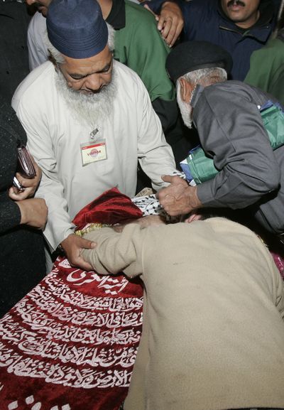 People comfort a family member who mourns over the dead body of slain police officer during a funeral in Lahore, Pakistan, on Tuesday.  (Associated Press / The Spokesman-Review)