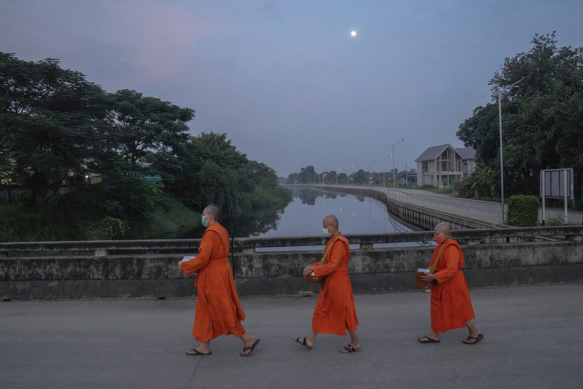 From left, Bhikkhuni Dhammavanna, Bhikkhuni Dhammaparipunna and Bhikkhuni Dhammasumana walk to collect alms from devotees in Nakhon Pathom province on Sunday, Nov. 21, 2021. Women are banned from becoming monks in Thailand, where over 90% of the population is Buddhist. Historically, women could only become white-cloaked nuns often treated as glorified temple housekeepers. But dozens have traveled to Sri Lanka to receive full ordination.  (Sakchai Lalit)