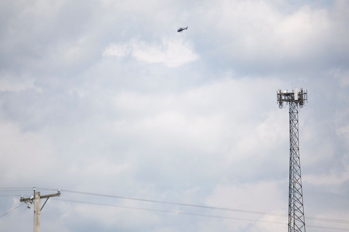 A helicopter flies over a field as authorities search for an armed man accused of trying to break into the FBI