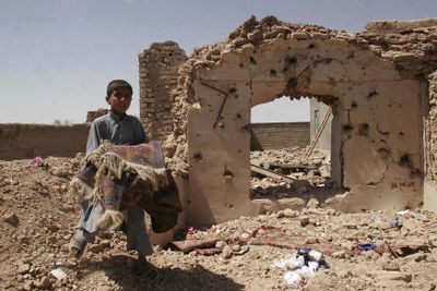 An Afghan boy carries his belongings next to the rubble of his home in the village of Azizabad, destroyed in a U.S. airstrike. (Associated Press / The Spokesman-Review)