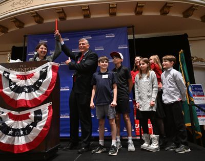 Outgoing 5th District Rep. Cathy McMorris Rodgers, left, hands a symbolic baton to Rep.-elect Michael Baumgartner after early results show him with a generous lead over Democrat opponent Carmela Conroy on Tuesday in the ballroom of the Historic Davenport Hotel in Spokane. To the right of Baumgartner are his five children and wife, Eleanor.  (Jesse Tinsley/The Spokesman-Review)