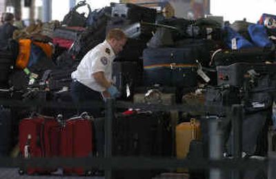 
A Transportation Security Administration worker is surrounded by stacked lost luggage on Sunday at Cincinnati/Northern Kentucky International Airport.
 (Associated Press / The Spokesman-Review)