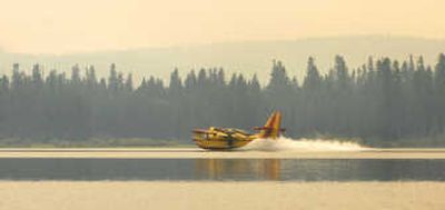 
A firefighting plane scoops up  water from Seeley Lake in Montana on Sunday to help fight a wildfire. More than a dozen large wildfires were burning in the state.Associated Press
 (Associated Press / The Spokesman-Review)