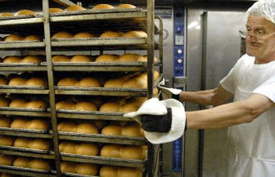
HearthBread Bakehouse baker Jusuf Buljubasic removes from the oven a rack of Zip's hamburger buns made with Shepherd's grain flour.
 (Dan Pelle / The Spokesman-Review)