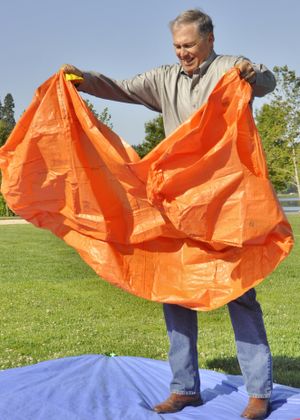 OLYMPIA -- Gov. Jay Inslee deploys a practice fire shelter during an exercise to emphasize preparations for Washington's fire season. (Jim Camden/Spokesman-Review)