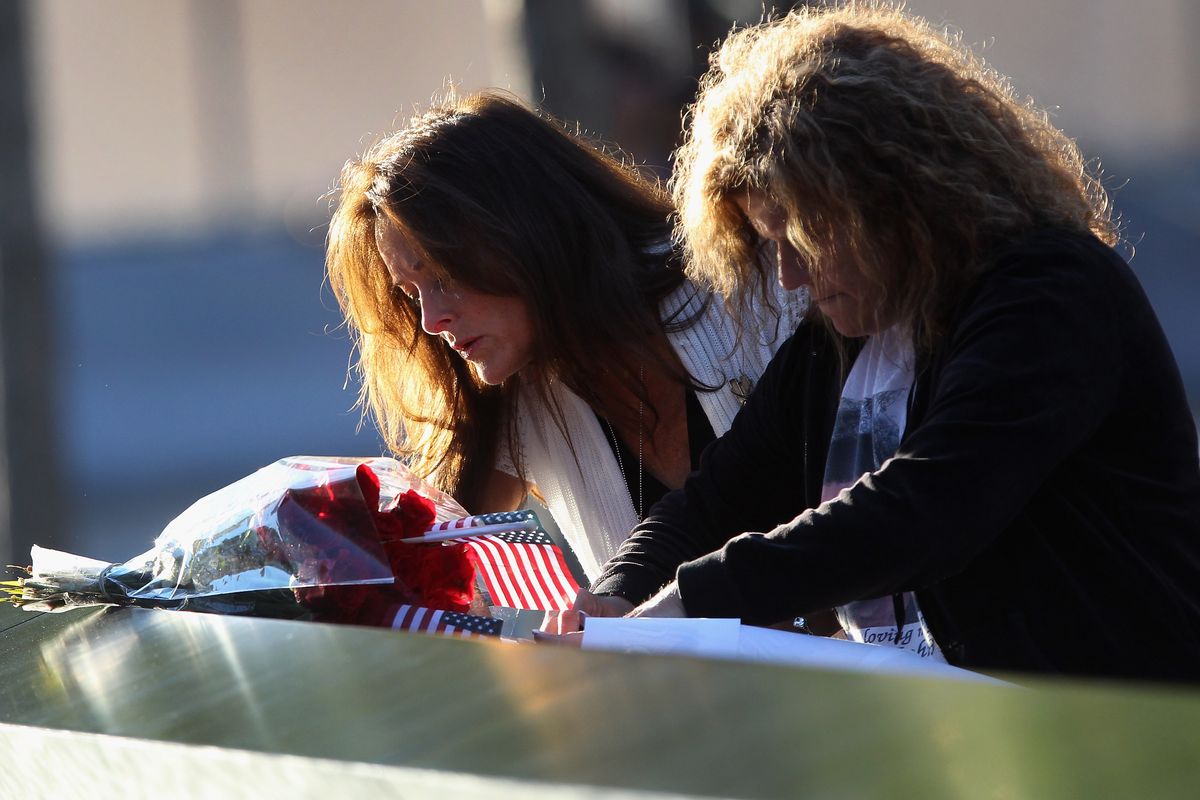 Tina Grazioso, left, looks at the name of her husband, John Grazioso, who died in the Sept. 11 terrorist attacks on the World Trade Center, during the 11th anniversary observance of the attacks at the World Trade Center Memorial in New York, Tuesday, Sept. 11, 2012. At right is John Grazioso