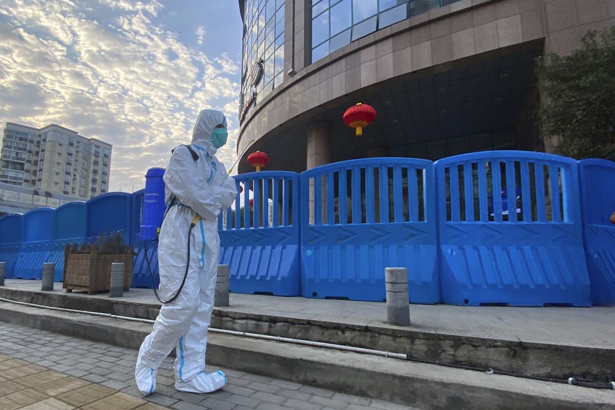 In this Feb. 6, 2021 photo, a worker in protectively overalls and carrying disinfecting equipment walks outside the Wuhan Central Hospital where Li Wenliang, the whistleblower doctor who sounded the alarm and was reprimanded by local police for it in the early days of Wuhan