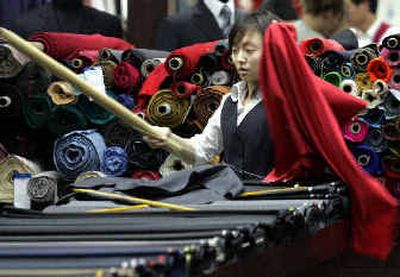 
A Chinese vendor measures out fabric at the Alice Tailor Shop in Beijing, China.  
 (Associated Press / The Spokesman-Review)