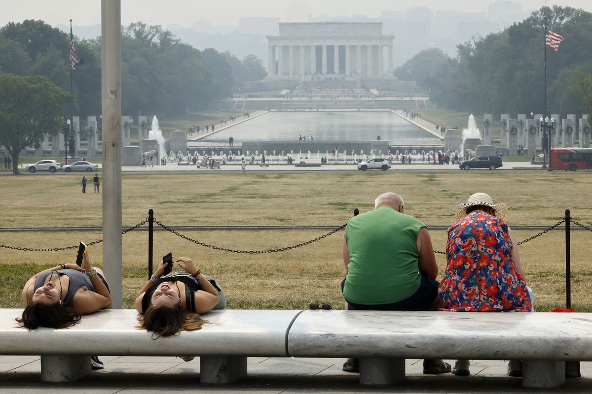 Tourists sit on benches at the base of the Washington Monument as wildfire smoke puts a veil of haze in front of the Lincoln Memorial along the National Mall on Thursday in Washington, D.C.  (Getty Images)