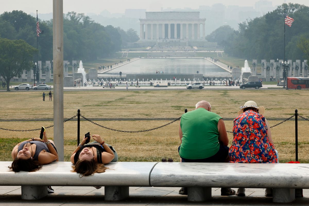 Tourists sit on benches at the base of the Washington Monument as wildfire smoke puts a veil of haze in front of the Lincoln Memorial along the National Mall on Thursday in Washington, D.C.  (Getty Images)