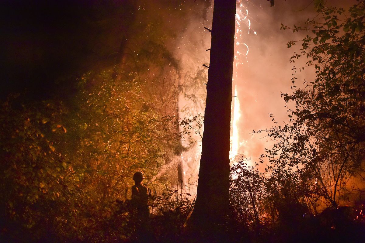 Melanie Brashler, of Stevens County Fire District 5, works to fight a flare-up of a massive wildfire along Townsend-Sackman Road early Saturday near Addy, Wash. (Tyler Tjomsland)