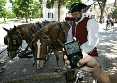 
An iPod plays a audio podcast as historical interpreter Dan Hand hitches Captain, left, and Ranger, to a wagon in Colonial Williamsburg, Va. 
 (Associated Press / The Spokesman-Review)