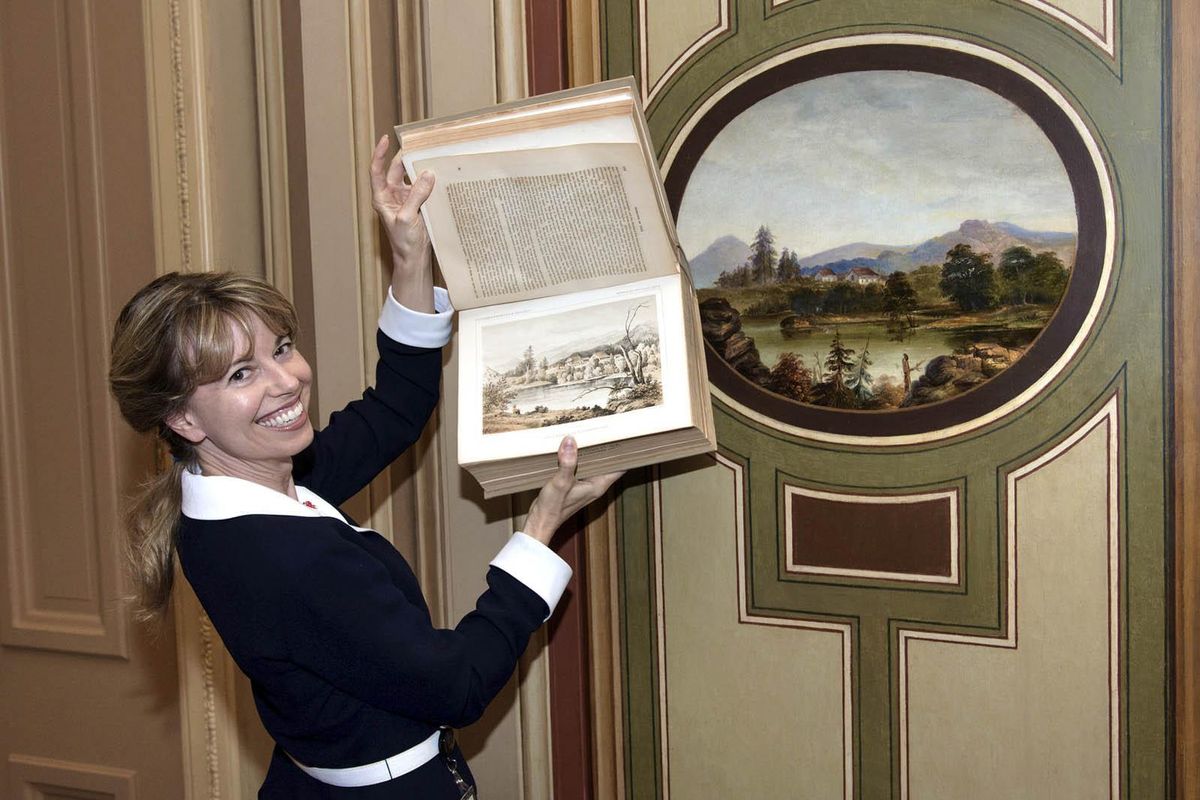 Amy Burton holds the Pacific Railroad Survey volume where she found the Old Mission lithograph. The Cataldo landscape medallion is on the wall behind her. (U.S. Senate photo / U.S. Senate Photo)