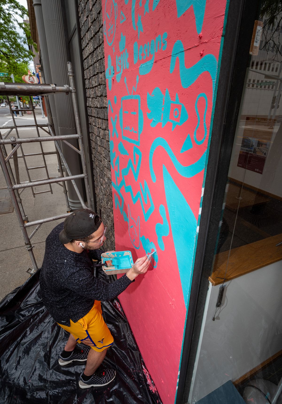 Graphic artist Joshua Thomas paints a mural of whimsical characters Saturday on a boarded-up window at the Empire State Building on West Riverside Avenue.  (COLIN MULVANY/The Spokesman-Review)