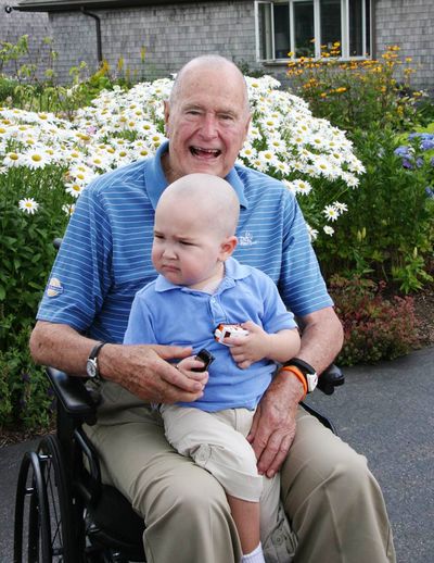 Former President George H.W. Bush sits with Patrick, 2, in Maine on Wednesday. (Associated Press)