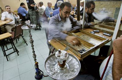 Palestinians smoke and play backgammon after breaking their daily fast during Ramadan in a coffee shop in the West Bank city of Ramallah.  (Associated Press / The Spokesman-Review)