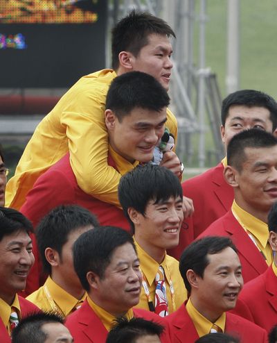 A Chinese athlete, top, knows how to get the publicity, jumping onto basketball star Yao Ming during a group photo session last month at the Athletes Village in Beijing.  (Associated Press / The Spokesman-Review)
