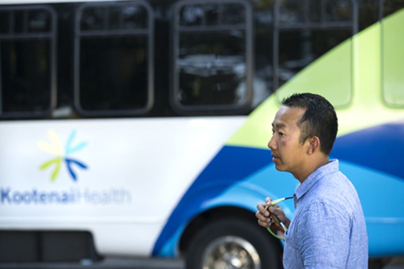 Ben Tran, of the local graphic design company Tran Creative, stands in front of a bus decorated with the new Kootenai Health logo which he spent over a year designing, at the launch of the new brand Tuesday evening at Kootenai Medical Center. (Gabe Green/press / D=cda S=color)
