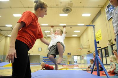 Instructor Holly Wohr teaches Aaron Ryder, 2, to swing on a bar during a class Thursday at the YMCA in Riverfront Park. The city has until Wednesday to abide by its agreement to buy the facility, originally reached to prevent a condo development.  (Jesse Tinsley / The Spokesman-Review)
