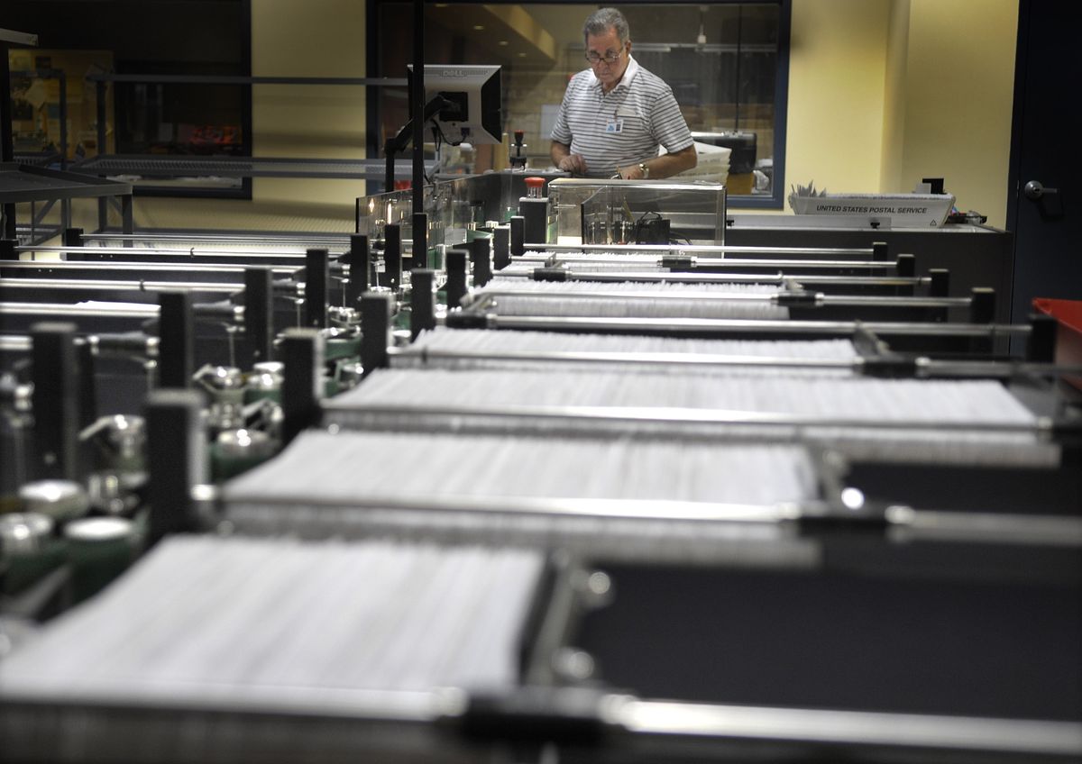 Spokane County election worker Gary Marcus watches as a new automated sorting machine processes a batch of ballots Friday. Election workers expect to have more than half of the ballots counted today.  (CHRISTOPHER ANDERSON / The Spokesman-Review)