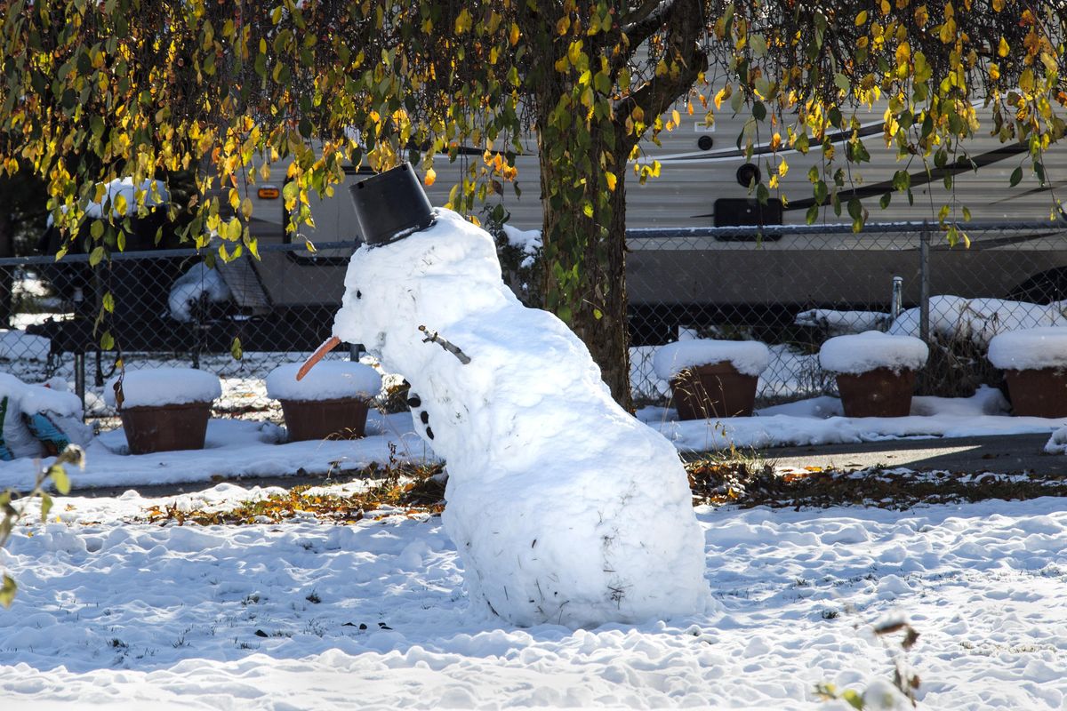 A snowman, sporting a flower pot for a hat, leans a little to the east, Monday, Nov. 6, 2017, near the corner of 40th Avenue and Latawah Street. (Dan Pelle / The Spokesman-Review)