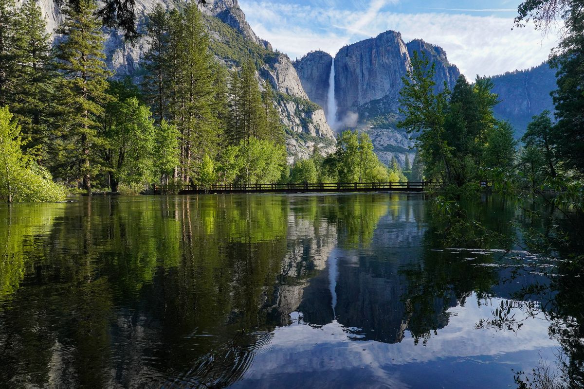 Upper Yosemite Falls is reflected in the Merced River at Swinging Bridge in Yosemite National Park, Calif., on June 13, 2023.    (Tracy Barbutes/For The Washington Post)
