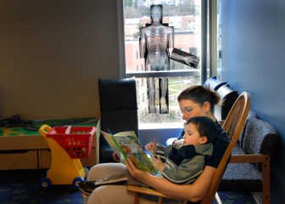 
Sacred Heart child care worker Amanda Douglas reads to Ty Gallimore, 3, on Tuesday  while his mother visits with his sister, who is being treated at the Spokane hospital. 
 (Brian Plonka / The Spokesman-Review)