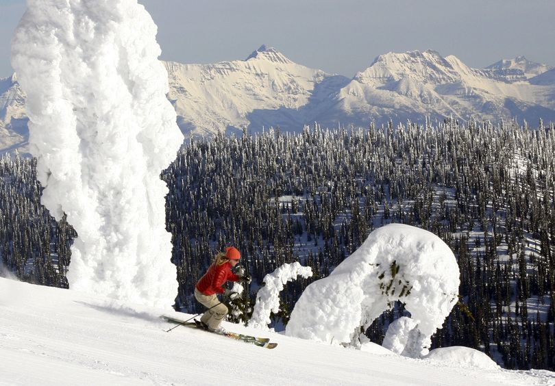A skier near the summit of Big Mountain at Whitefish Mountain Resort in Montana glides by the signature snow ghosts with the peaks of Glacier National Park in the background.  (Brian Schott / Associated Press)