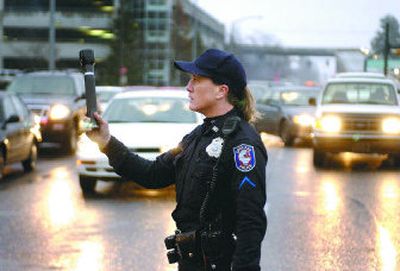 
Spokane police Officer Davida Zinkgraf directs traffic Sunday on Wellesley Avenue outside the NorthTown mall parking structure. The mall evacuation caused a backup that resulted in some drivers needing an hour to exit the garage and be on their way. 
 (Photos by J. BART RAYNIAK . / The Spokesman-Review)