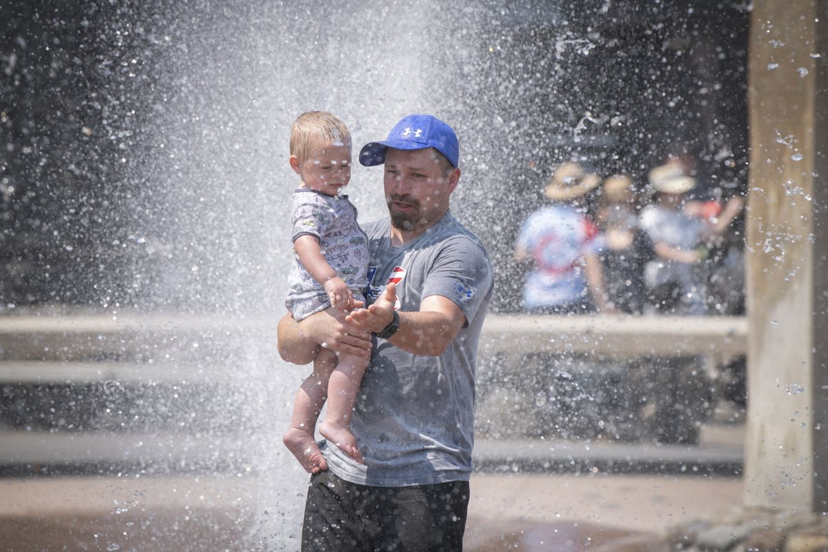 Ryan Allen of Moses Lake carries his 13-month-old son, Rainier Allen, through the Rotary Fountain in Riverfront Park on July 13 to cool down as temperatures reached into the low 90s around lunchtime.  (Jesse Tinsley/THE SPOKESMAN-REVIEW)