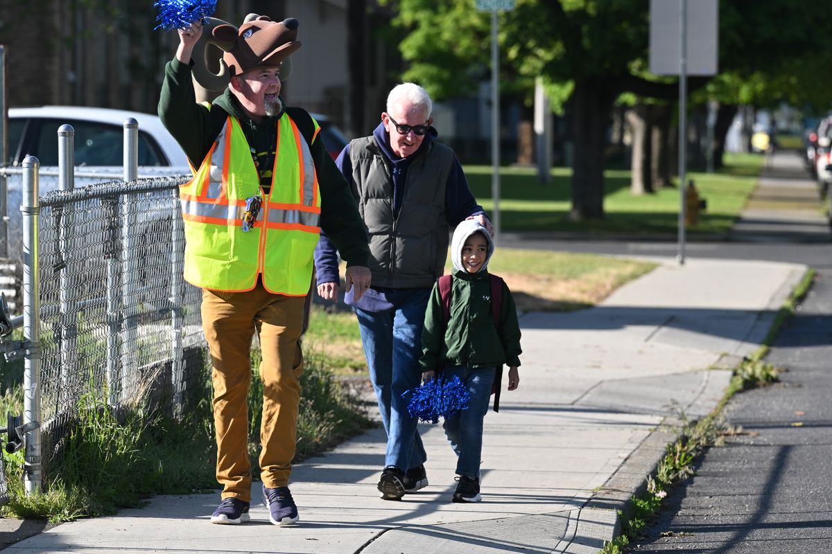 Simeon Bergstedt, left, the librarian at Regal Elementary, and volunteer Kevin Hutton walks a student to the school on May 20 as part of the “walking bus” program. Bergstedt often includes a funny hat as part of his attire during morning walks. (Jesse Tinsley/The Spokesman-Review)