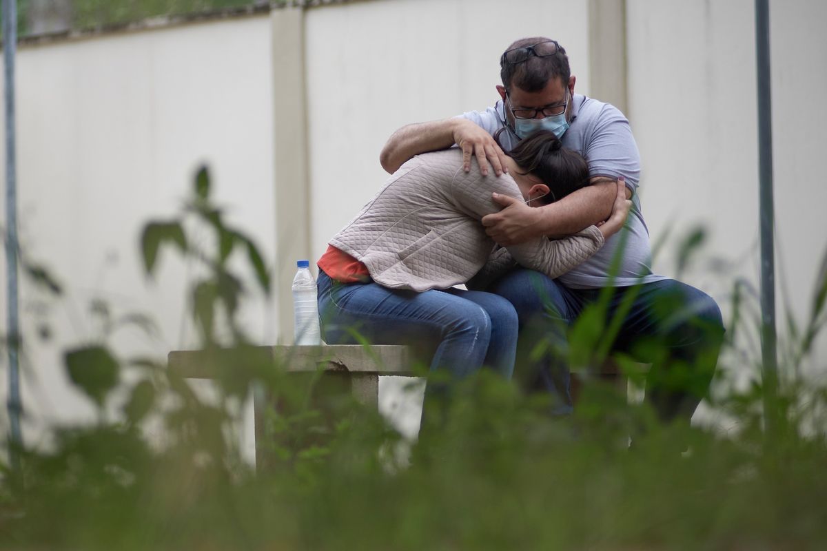A couple embraces as they wait for information about missing relatives after a massive slab of rock broke away from a cliff and toppled onto pleasure boaters at Furnas reservoir on Saturday, killing at least seven people, near Capitolio city, Brazil, Sunday, Jan. 9, 2022.  (Igor do Vale)