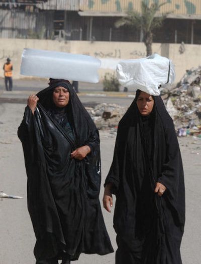 
Two Iraqis carry blocks of ice on top of their heads Saturday in Baghdad, Iraq. With temperatures rising above 120 degrees, many can only afford ice to bring comfort in the heat. 
 (Associated Press / The Spokesman-Review)