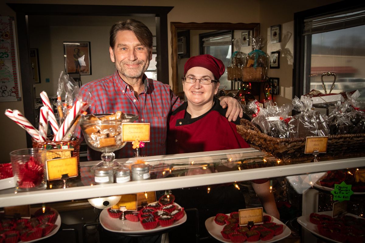 Sandpoint Chocolate Bear co-owners Dennis and Carrie Powell pose for a photo behind the counter at their shop,] on Dec. 16, 2019. The original chocolate shop burned down in the February fire that destroyed several Sandpoint businesses, but the husband-wife duo relocated the shop to Spokane Valley, where it has been up and running since summer at 11425 E. Trent. (Libby Kamrowski / The Spokesman-Review)