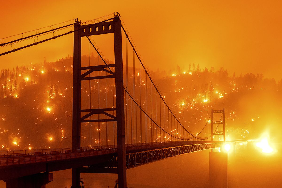 FILE - In this Sept. 9, 2020, file photo, taken with a slow shutter speed, embers light up a hillside behind the Bidwell Bar Bridge as the Bear Fire burns in Oroville, Calif. Two unusual weather phenomena combined to create some of the most destructive wildfires the West Coast states have seen in modern times.  (Noah Berger)