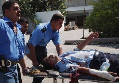 
An injured policeman is rushed to the hospital after a suicide bombing in Iraq.
 (Associated Press / The Spokesman-Review)