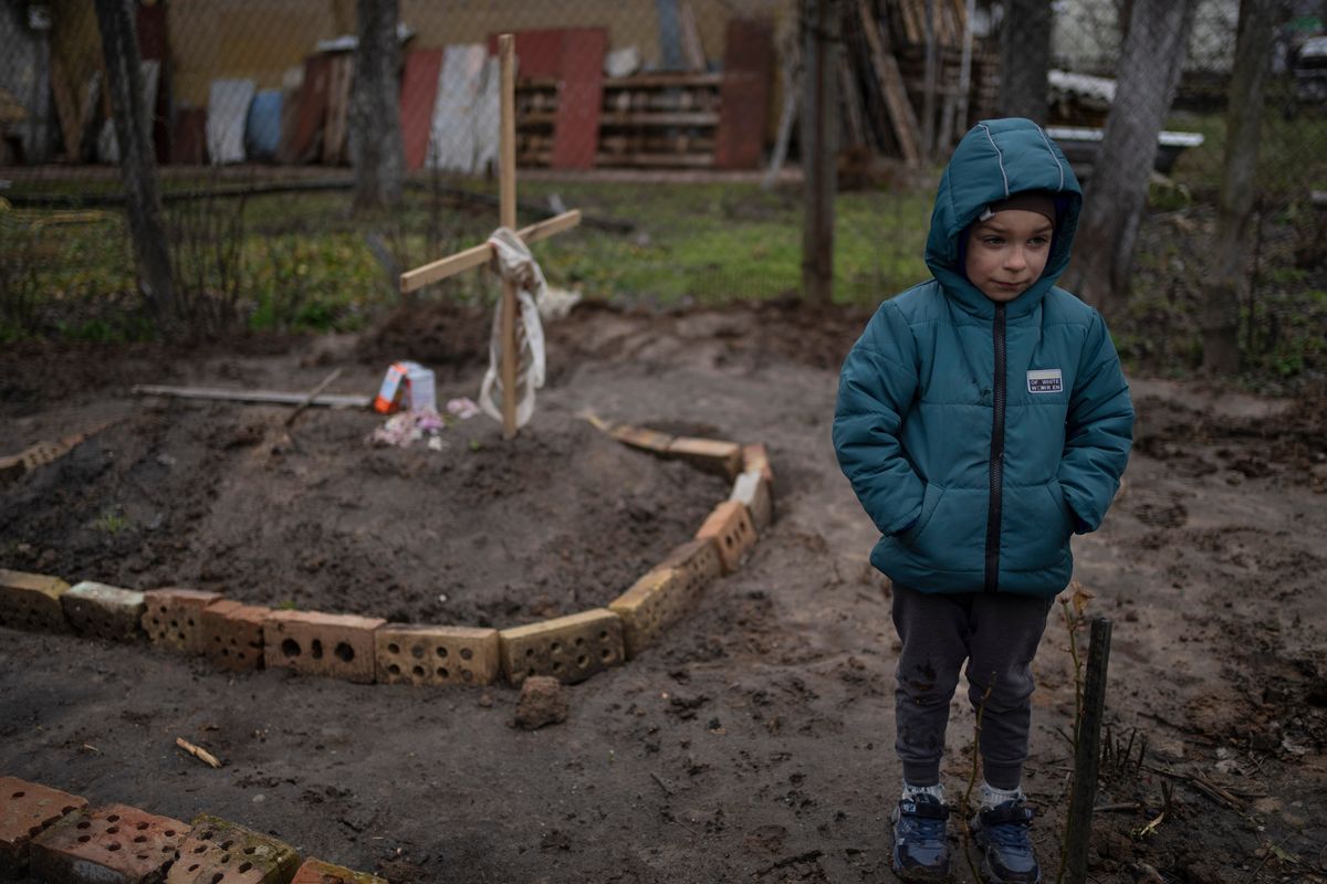 FILE - In the courtyard of their house, Vlad, 6, stands near the grave of his mother, who died, on the outskirts of Kyiv, Ukraine, Monday, April 4, 2022. Vlad