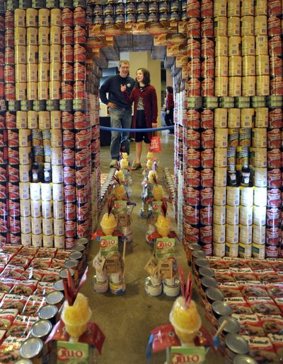 Bill Osborne and his daughter Esther Osborne, 13, admire the “Arc de Triomphe Over Hunger” canned food structure, one of six on display in the lobby of River Park Square. Local architectural firms built the structures. (Colin Mulvany)