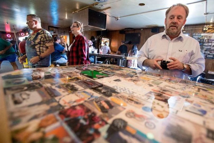Bob's 21 Club owner Bobby Wilhelm looks over a table top that was recently renovated with historical artifacts encased in resin as part of a makeover of the bar on Friday at the bar's Post Falls location. (Jake Parrish/Coeur d'Alene Press)