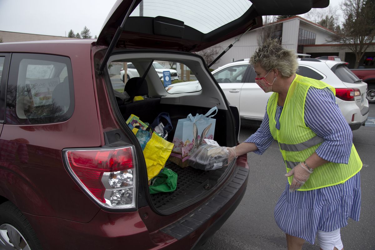 Chris Verheul, a libary assistant at the North Spokane Libarary, places a bag of books in the back of a patron’s car Wednesday, April 7, 2021 during abbreviated hours. Although the library will resume normal hours next week, staff will probably continue to offer curbside pickup services.  (Jesse Tinsley/The Spokesman-Review)
