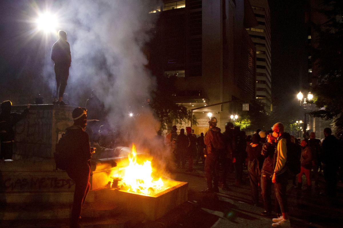 FILE - In this July 4, 2020, file photo, protesters gather near a fire in downtown Portland, Ore. Oregon