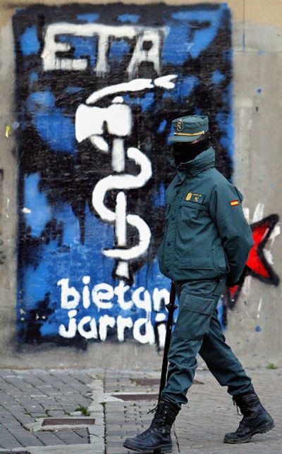 
A masked Spanish Civil Guard walks next to a wall painted with graffiti of the separatist group ETA in in Alsasua, northern Spain. 
 (Associated Press / The Spokesman-Review)