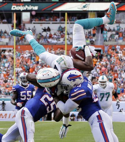 Miami Dolphins receiver Brandon Gibson, from Washington State, jumps over Da'Norris Searcy, left, and Aaron Williams of the Bills for a touchdown. (Associated Press)