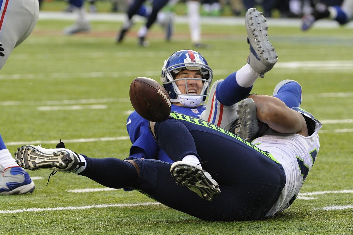 The football flies loose as Seahawks defensive end Michael Bennett, bottom, sacks Eli Manning, who threw five interceptions. (Associated Press)